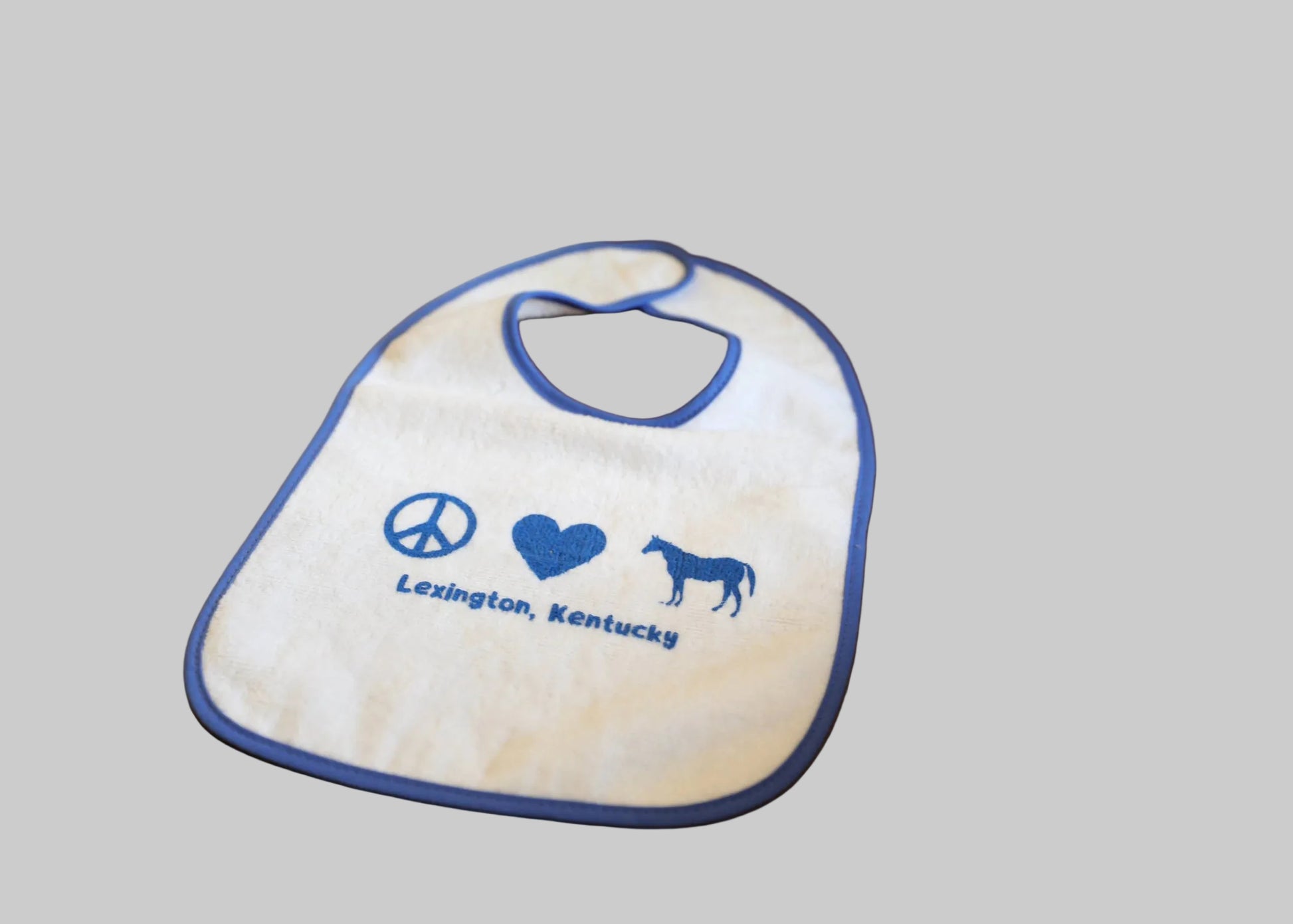 Baby bib with peace, love, and horse design on a wooden table