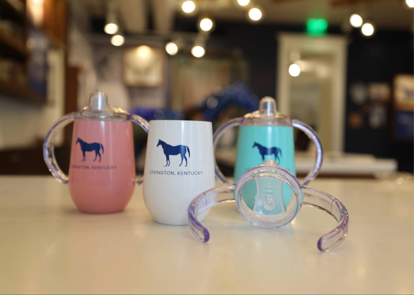 Three baby sippy cups with horse designs on a counter.